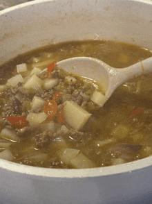 a bowl of soup with meat and potatoes and a spoon in it