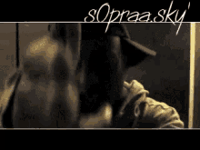 a man wearing a baseball cap and a jacket is standing in front of a sign that says sopraa sky