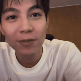 a close up of a man 's face wearing a white t-shirt