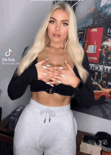 a woman in a black crop top and grey sweatpants has a tiktok sticker on her chest