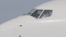 a pilot sits in the cockpit of an airplane with a clear window