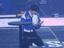 a man in a blue jacket with nasa on it is kneeling on a stage