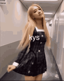 a woman in a black dress is standing in a hallway with the word kys written on the bottom