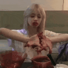 a woman is sitting at a table with blood coming out of her mouth while eating food .