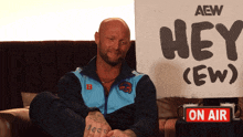 a man is sitting in front of a sign that says hey ( ew )