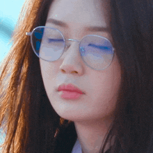 a close up of a woman wearing round glasses with her eyes closed