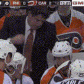 a group of hockey players are sitting in a stadium with a referee .