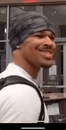 a man wearing a black beanie and a white shirt is smiling .