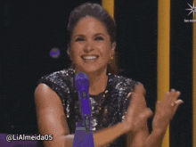 a woman sitting in front of a microphone with the hashtag lialmeida05 at the bottom
