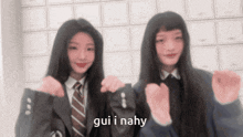 two girls in school uniforms are making a heart shape with their hands and the words gui i nahy are on the bottom of the image