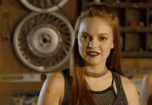 a woman wearing a choker is standing in front of a motorcycle wheel .