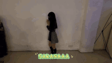a girl standing in front of a wall with the word sakanaaa written on the floor