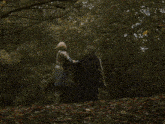 two people standing next to each other in the woods