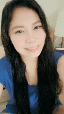 a woman in a blue shirt is smiling and taking a selfie