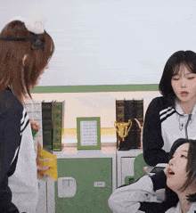 two girls are sitting in front of a green locker with a trophy on top of it