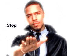 a man in a suit and tie is giving a stop sign .