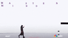 a man in a trench coat stands in front of a screen that says mastermind on it