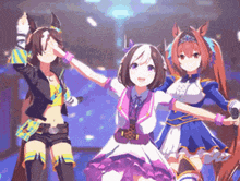 three anime girls are standing next to each other on a stage with their hands in the air .