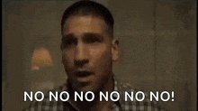 a man in a plaid shirt is standing in a dark room and says `` no no no no no no no ! ''