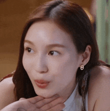 a close up of a woman making a face with her hand on her chin