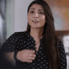 a woman in a black and white polka dot shirt is smiling and talking .