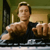 a man in a blue shirt is typing on a computer keyboard