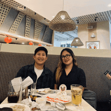 a man and a woman sit at a table with a duck king sticker on a plate