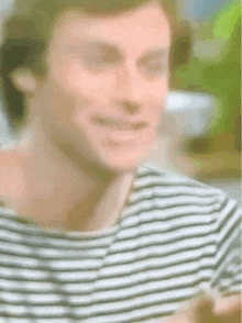 a blurry picture of a man wearing a striped shirt smiling