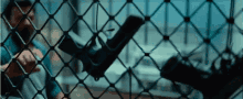 a man is holding a gun behind a chain link fence .
