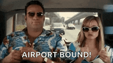 a man and a woman are sitting in a car and the woman is giving a thumbs up .