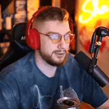 a man wearing headphones and glasses is sitting in front of a microphone in a room .