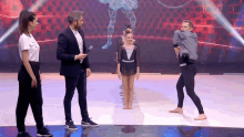 a group of people standing on a stage with a man holding a microphone