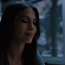 a woman is sitting at a table in front of a window in a dark room .