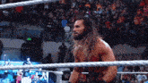 a man with long hair and a beard is in a wrestling ring with the letter w on the ropes