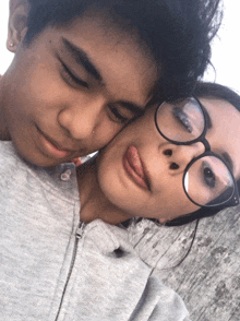 a boy and a girl are posing for a picture and the girl has her tongue out