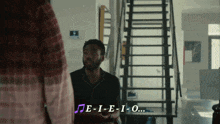 a man sitting in front of a staircase with e-i-e-i-o written on the bottom