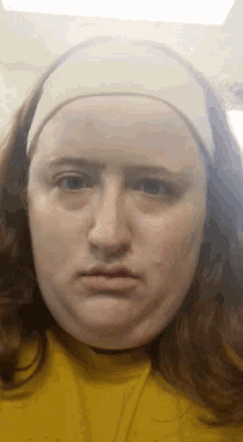 a woman wearing a yellow shirt and a white headband is making a funny face