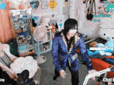 a man in a blue jacket is dancing in a room with stuffed animals on the shelves