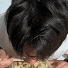 a close up of a person eating noodles from a plastic container