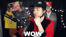 a man sitting in front of a microphone with wow written on his arm