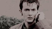 a man is talking on a cell phone while looking at the camera .