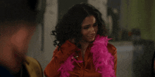 a woman is wearing a pink boa around her neck while talking to a man