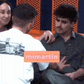 a man sitting next to a woman with a sign that says mimartin on it