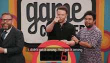 three men are standing in front of a sign that says game show