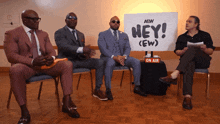 four men sit in front of a sign that says hey ( ew )