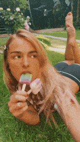 a woman laying on her stomach eating a popsicle