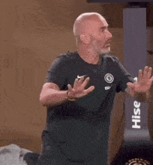 a bald man with a beard is wearing a black nike shirt and kneeling down .