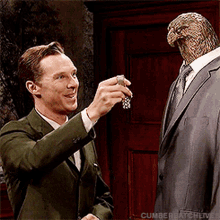 a man in a suit is holding something in front of a statue of a bird