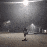 a woman is walking down a street at night in a parking lot