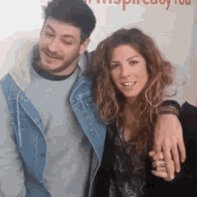 a man and a woman are posing for a picture and the woman has a ring on her finger .